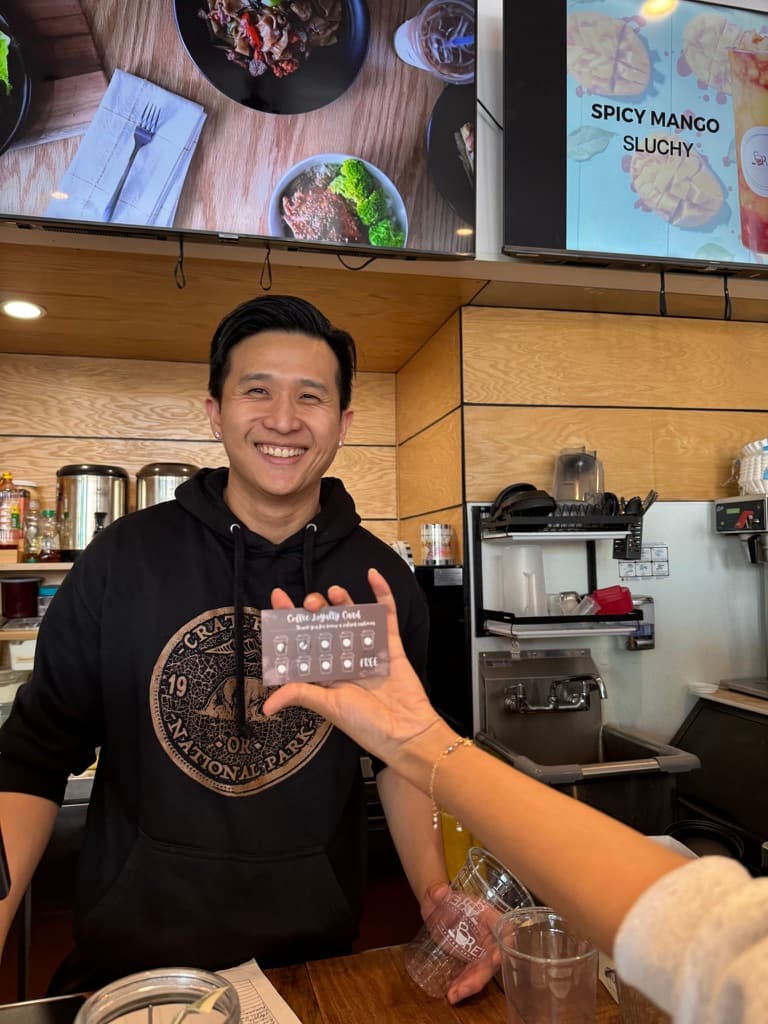 Barista holding a coffee loyalty punch card behind the counter