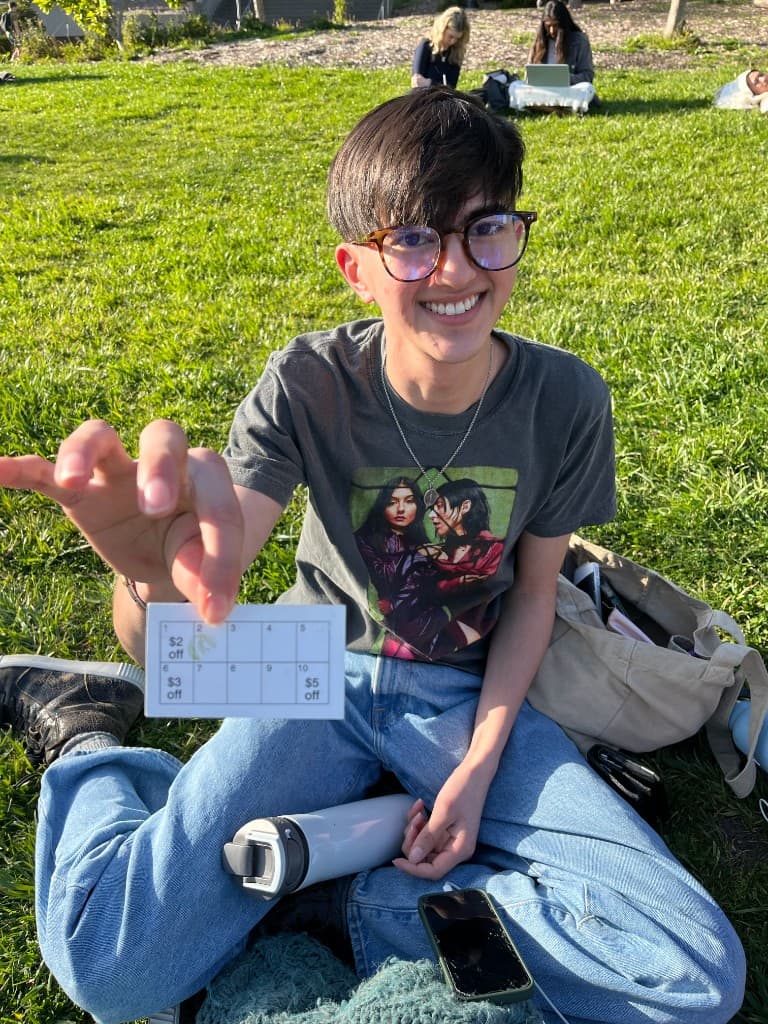 Numbered paper punch card with tiered rewards held in a park